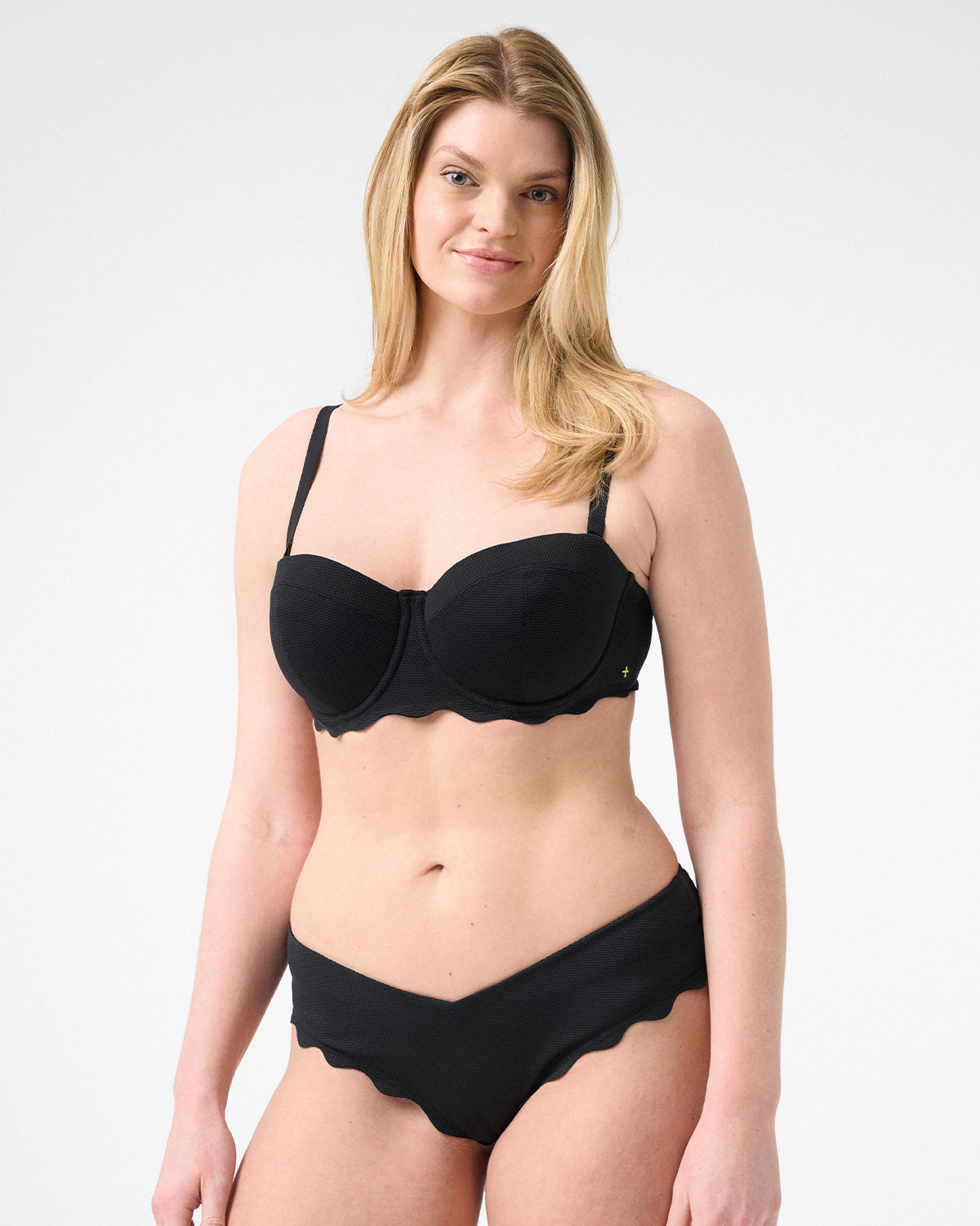 Woman wearing black colored bikini with scalloped edges