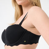 Side profile of woman wearing black colored bikini top with scalloped edges