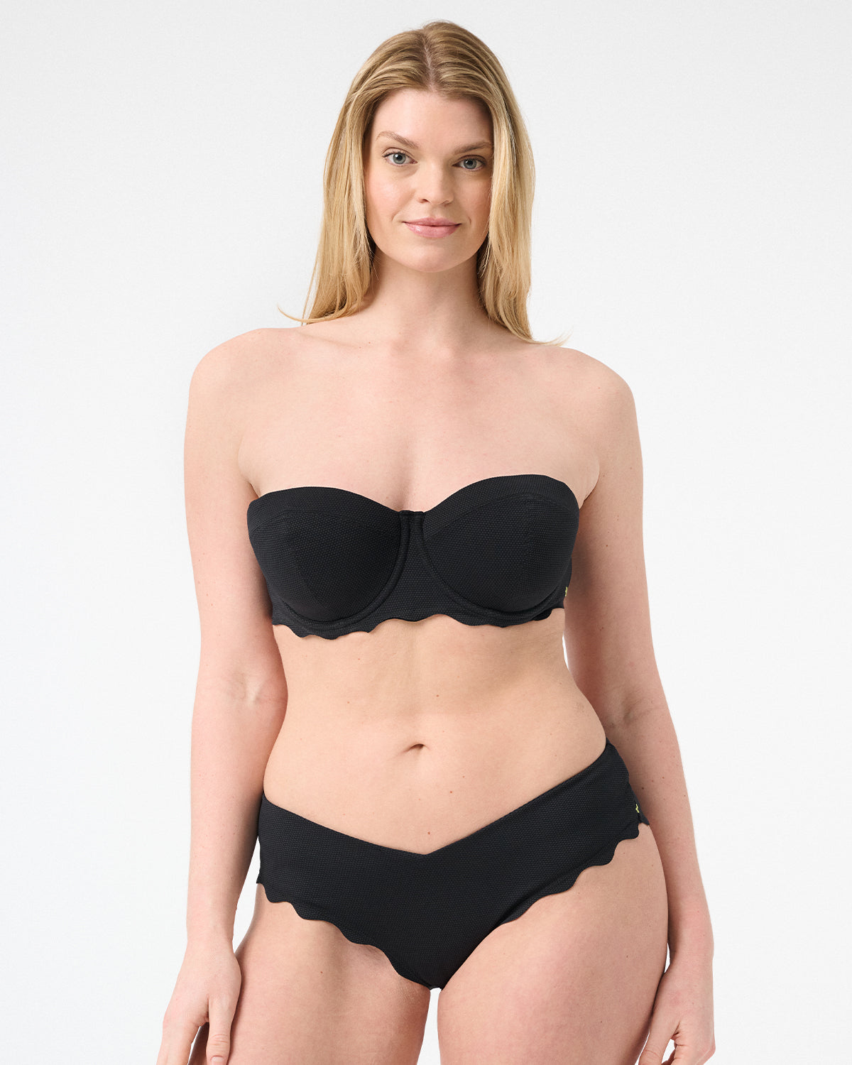Woman wearing black colored strapless bikini with scalloped edges