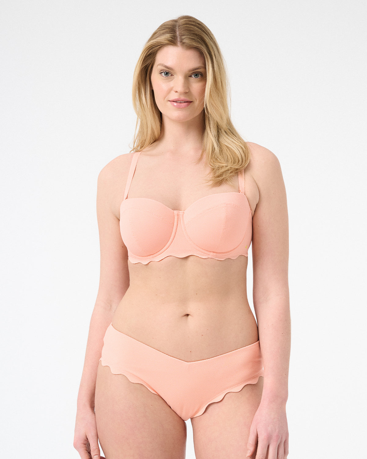 Woman wearing peach colored bikini with scalloped edges