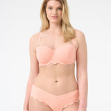 Woman wearing peach colored bikini with scalloped edges