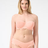 Woman wearing peach colored strapless bikini with scalloped edges