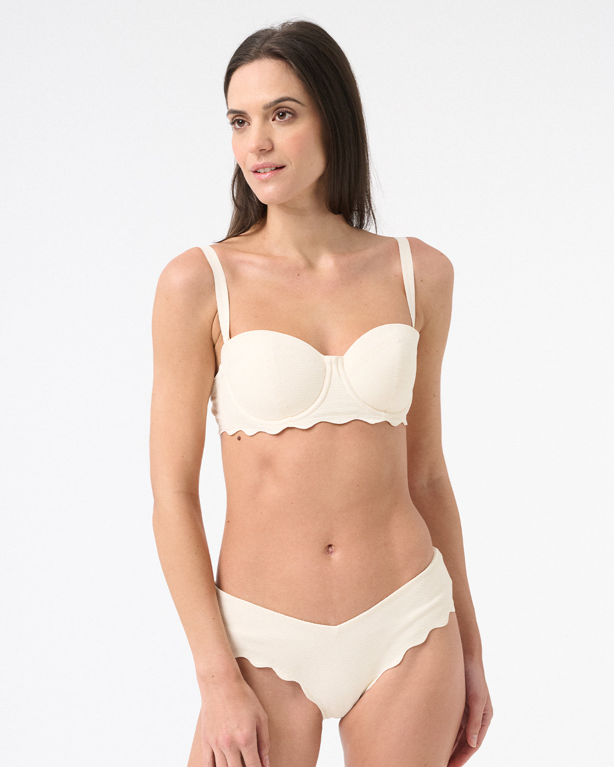 Woman wearing light cream bikini with scalloped edges