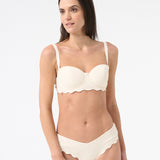 Woman wearing light cream bikini with scalloped edges