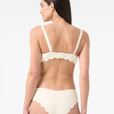 Back view of woman wearing light cream bikini with scalloped edges