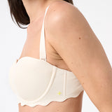Woman wearing light cream bikini top with scalloped edges