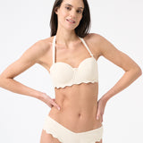 Woman wearing light cream bikini with scalloped edges