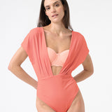 A model is wearing a coral one-piece swimsuit with a deep v-neckline and cap sleeve design.