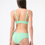 back of a woman wearing mint colored bikini with scalloped edges