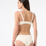 A side view of a person wearing a black textured bikini bottom with seamless leg openings.