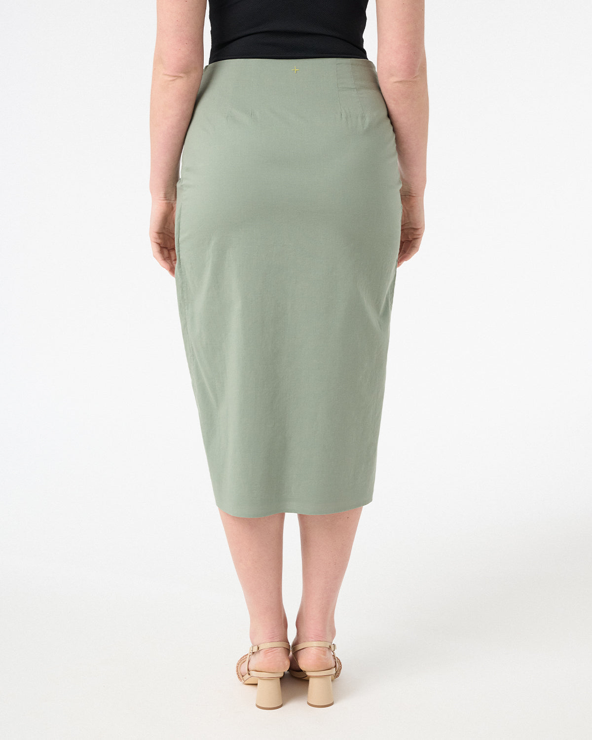 A woman wearing green wrap skirt with black swimsuit underneath