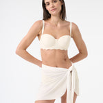 Close up of Woman wearing a  vanilla bikini top and vanilla wrap skirt on a white background