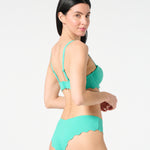 Side angle of model wearing Deep Dive textured balconette bikini top and matching scalloped Iris bikini bottoms by Siren + Sage