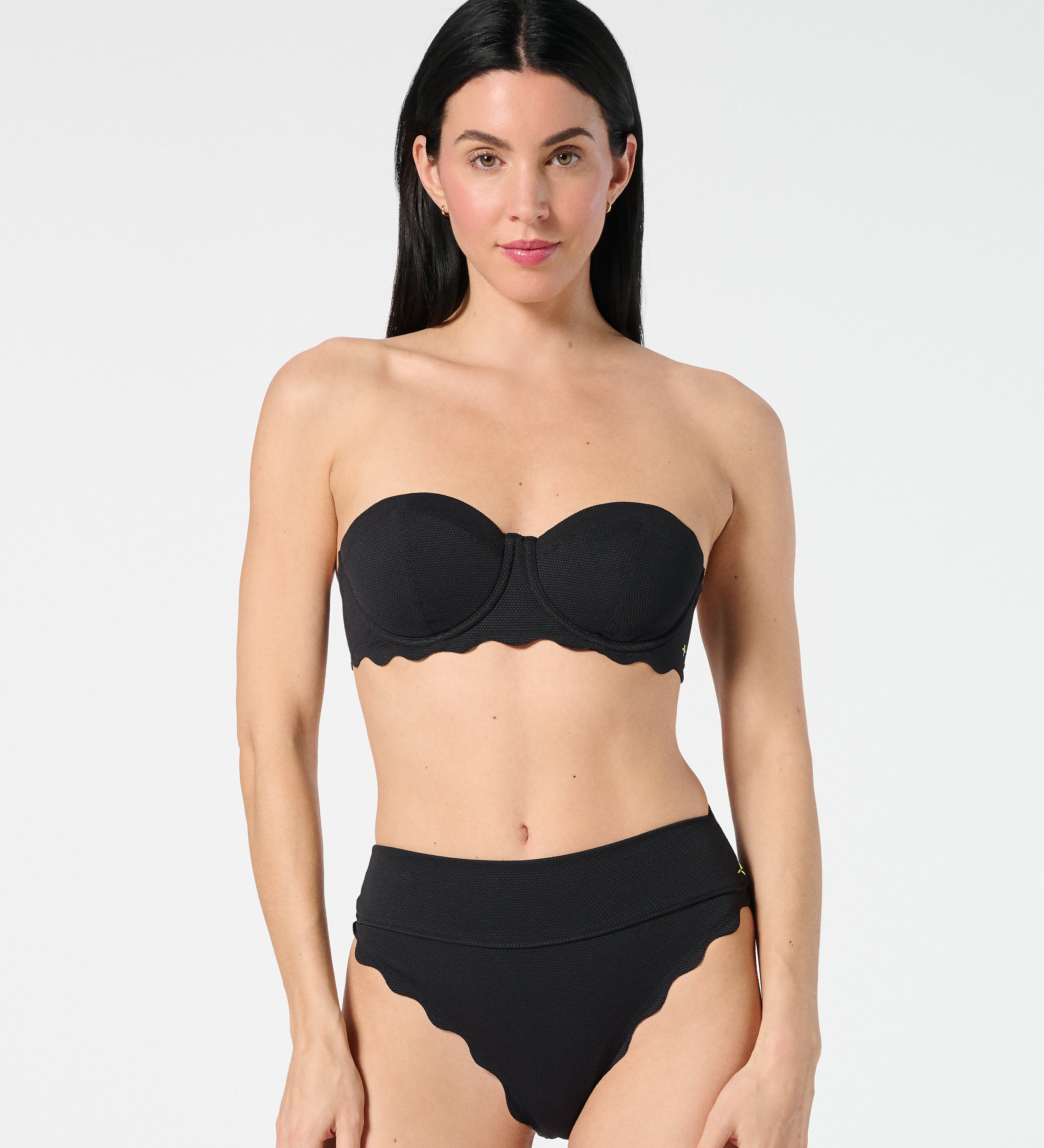 Model wearing a strapless look with black textured balconette bikini top and high-waisted scalloped bikini bottoms, featuring a sleek shaping fit