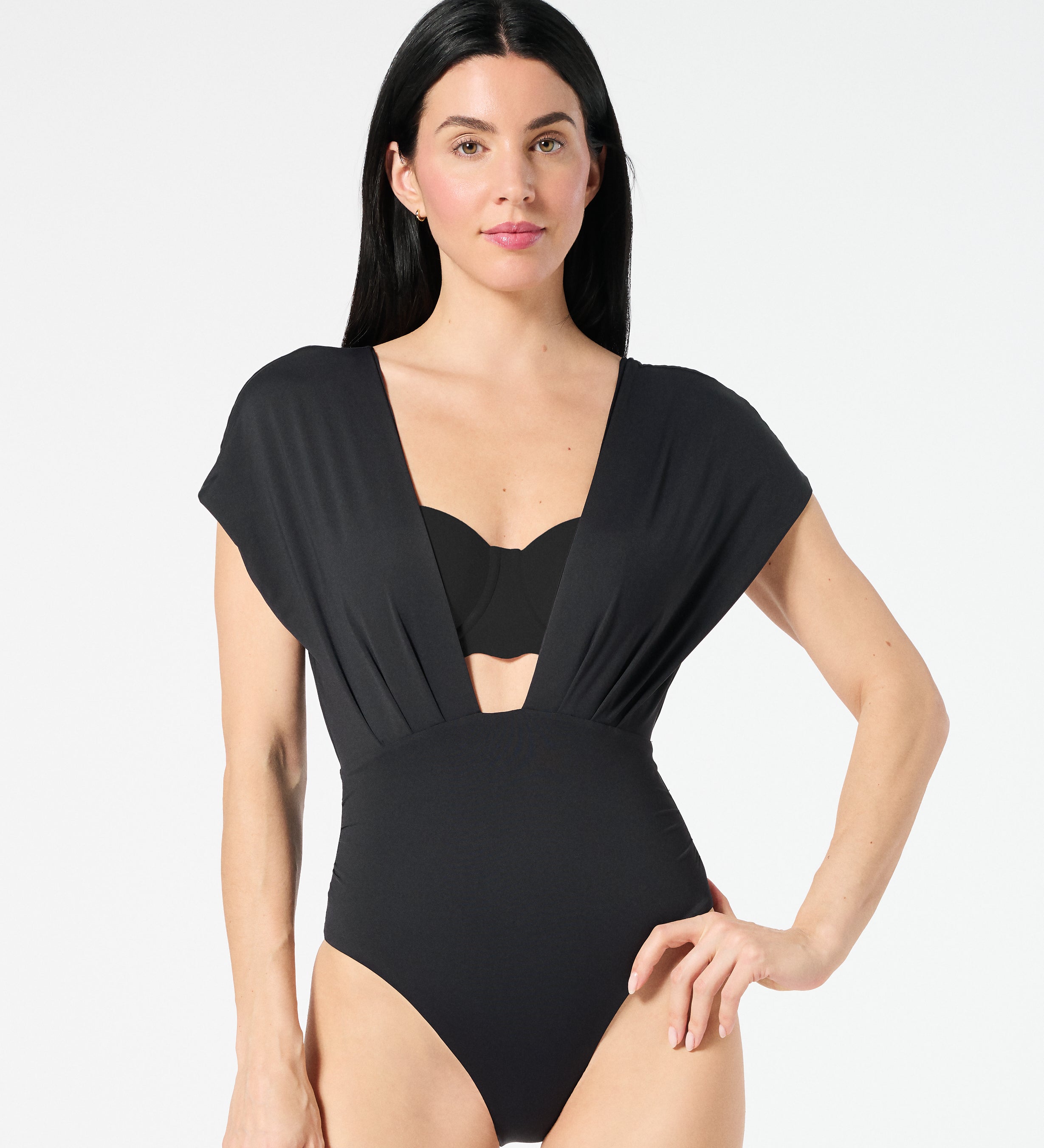 Woman wearing black Gaia OverKini layered over a balconette bikini top, providing sculpting coverage without flattening the bust