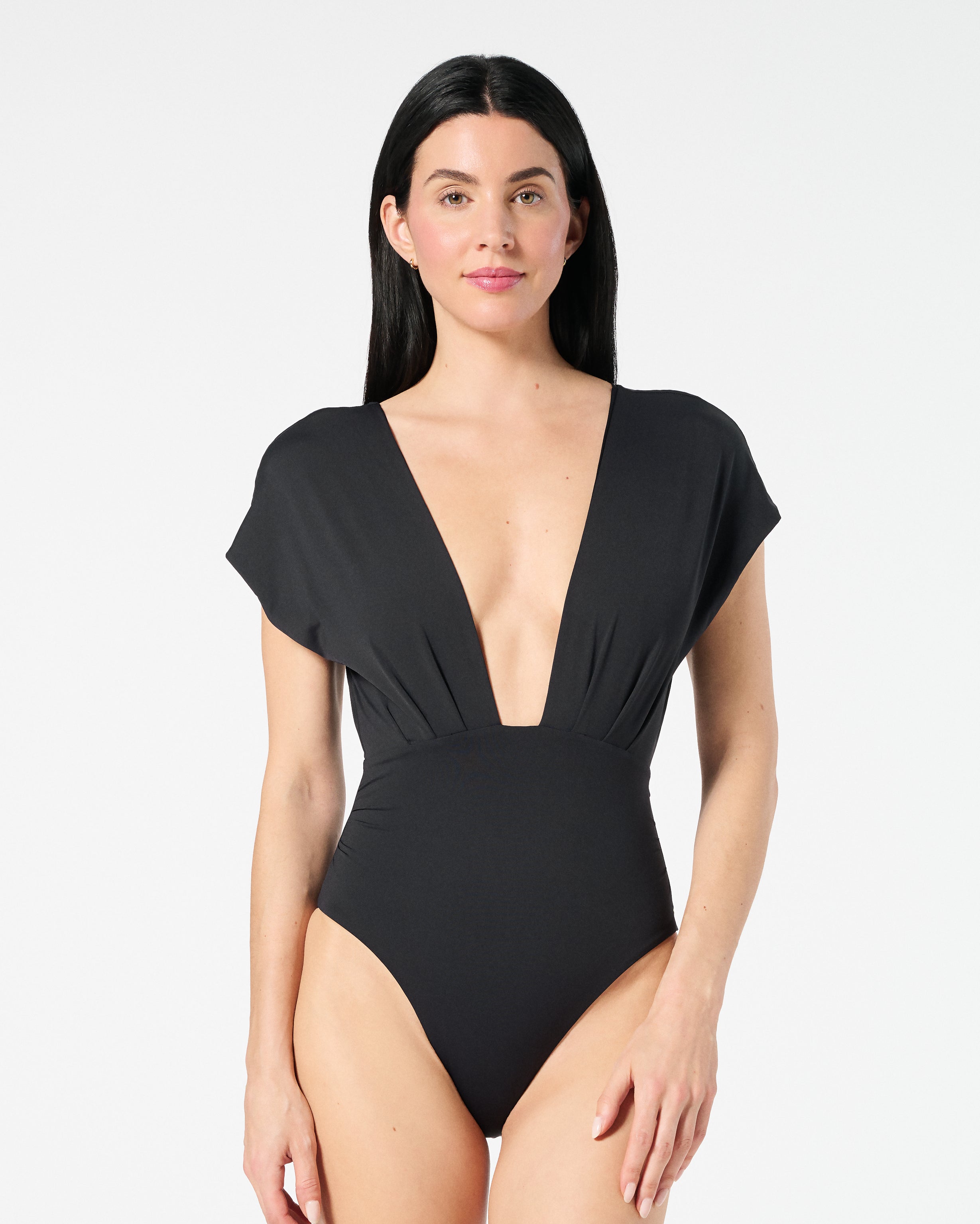 Woman wearing black Gaia OverKini with a deep V-front, sculpting one-piece design, and high-leg fit