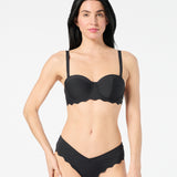 Woman wearing black balconette bikini top with bra-sized lift, smooth fabric, and convertible straps