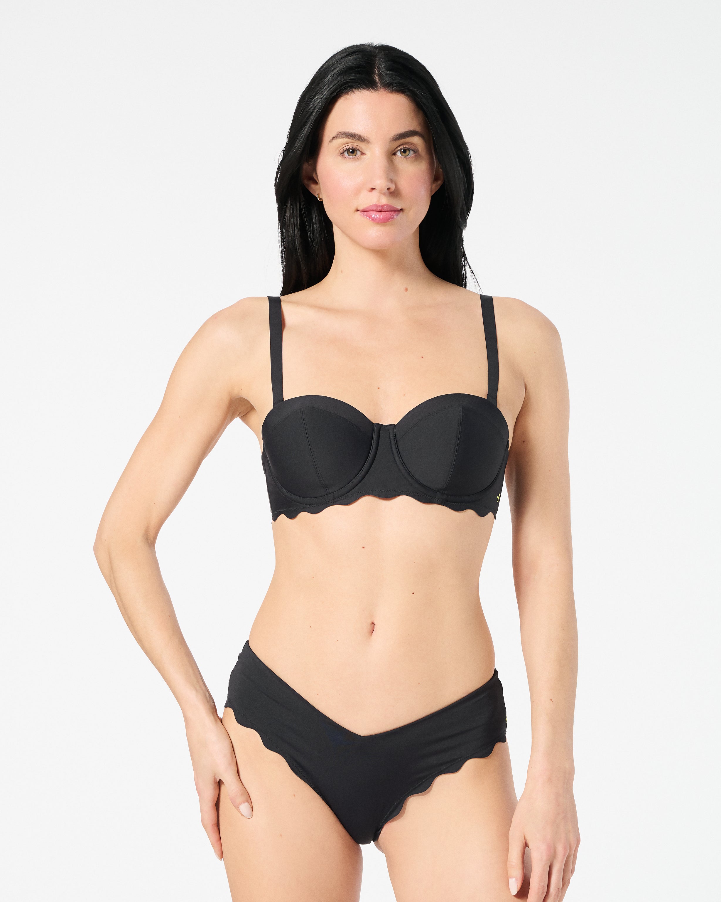 Woman wearing black balconette bikini top with bra-sized lift, smooth fabric, and convertible straps