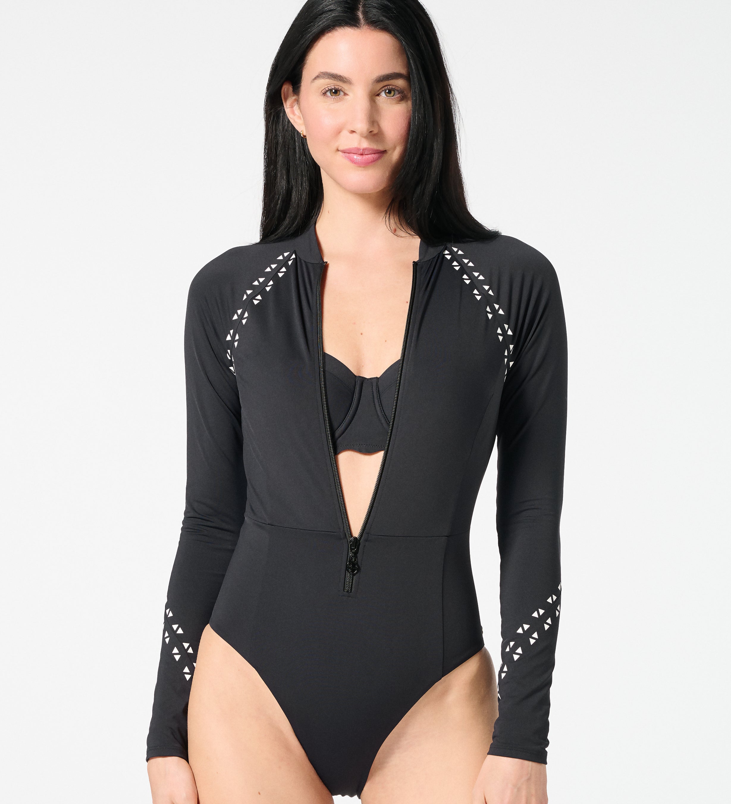 Woman wearing black long-sleeve surf suit layered over a supportive bikini top, showing versatile surf and swim styling